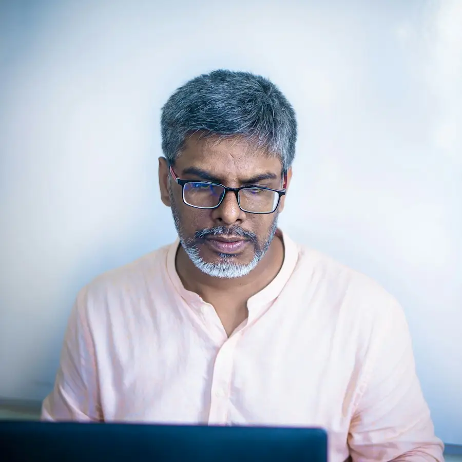 Man with glasses looking at a laptop