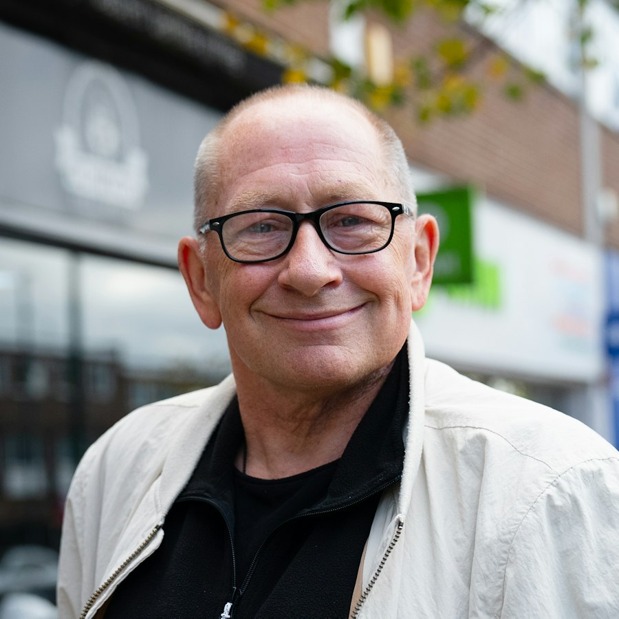 Man in glasses smiling on a high street
