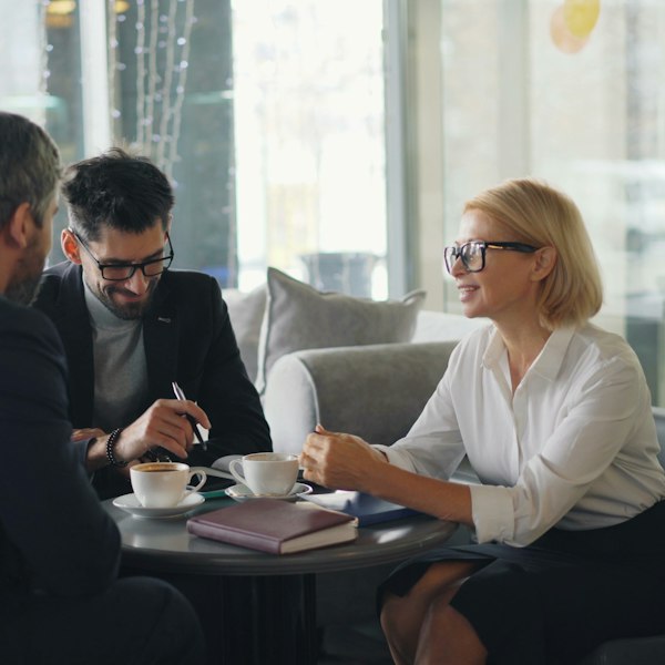 Three people in conversation over coffee