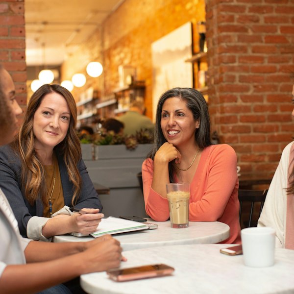 Four friends talking round a café table